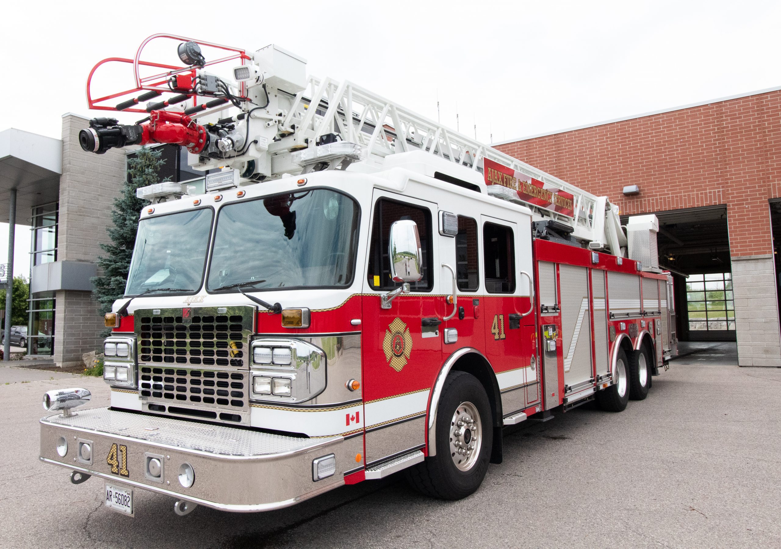 A red and white fire engine with the number 41 is parked outside a fire station.
