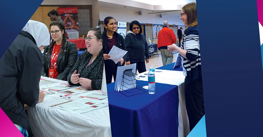 Two groups of women interact at information tables during an indoor event with brochures and informational materials displayed.
