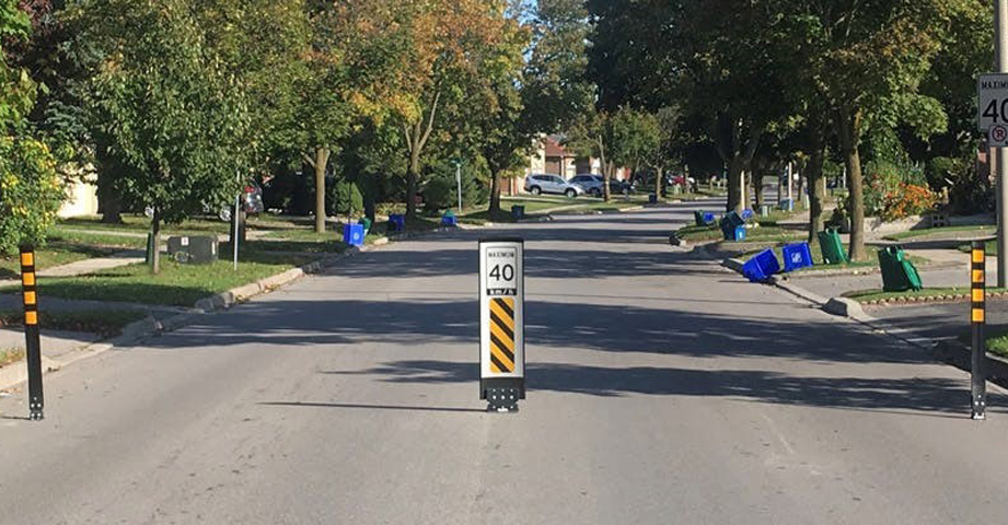 A residential street with a 40 km/h speed limit sign and traffic calming bollards in the centre of the road.