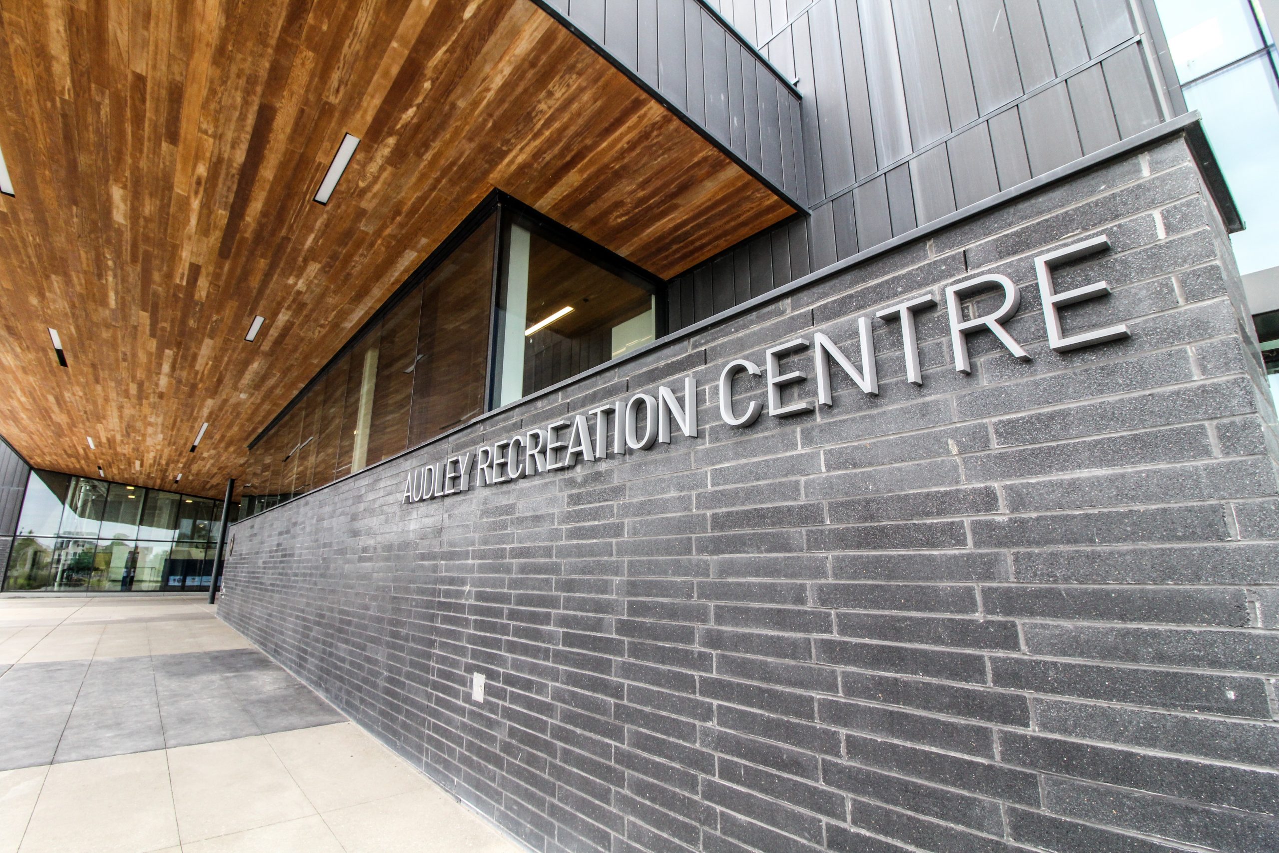 Exterior view of a modern building with a sign reading "Holley Recreation Centre" on a brick wall.