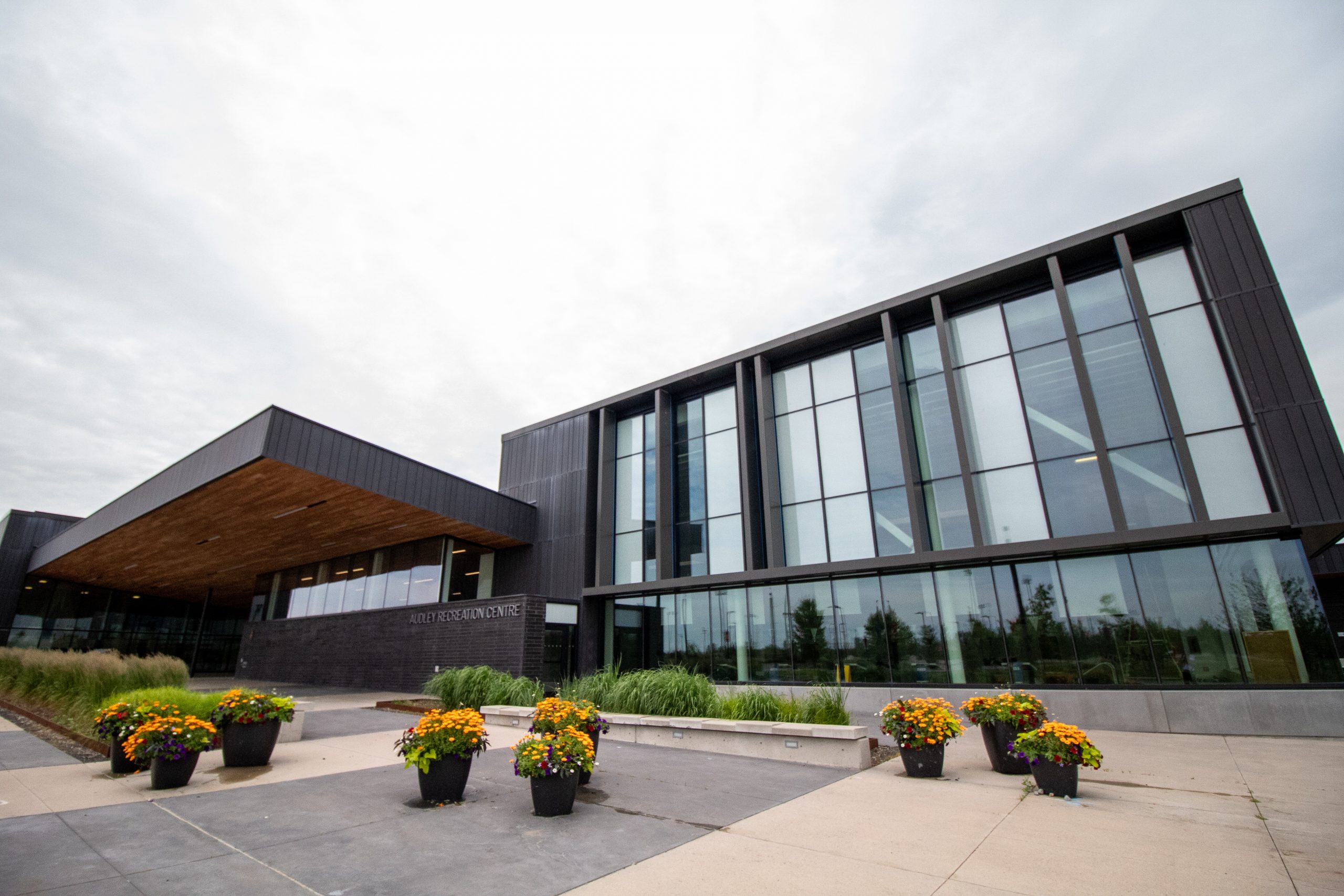 Modern building with large glass windows, a sloping roof, and planters—ideal for Preschool Recreation Programmes.