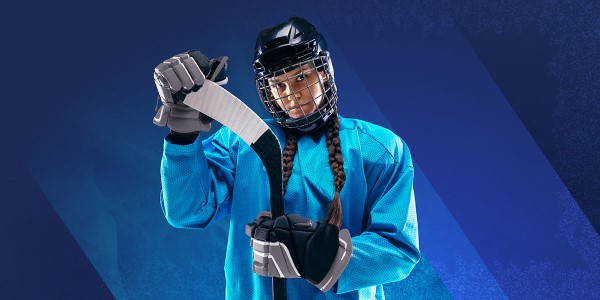 Girl with braids in full hockey gear holding a hockey stick.