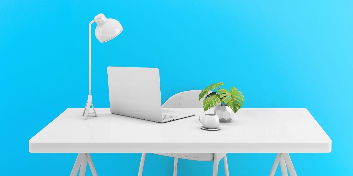 Illustration of a desk with a lamp, laptop and plant on it.