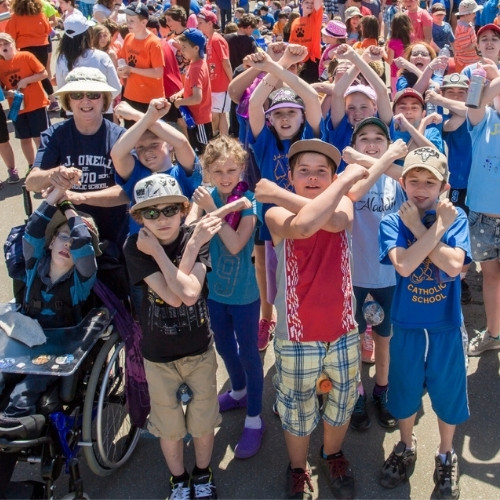 Kids with sunglasses and hats dance in a crowd.