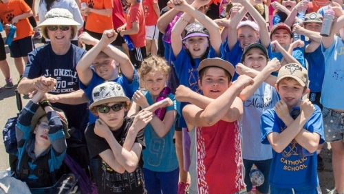 Kids in sunglasses and hats dance in a crowd.