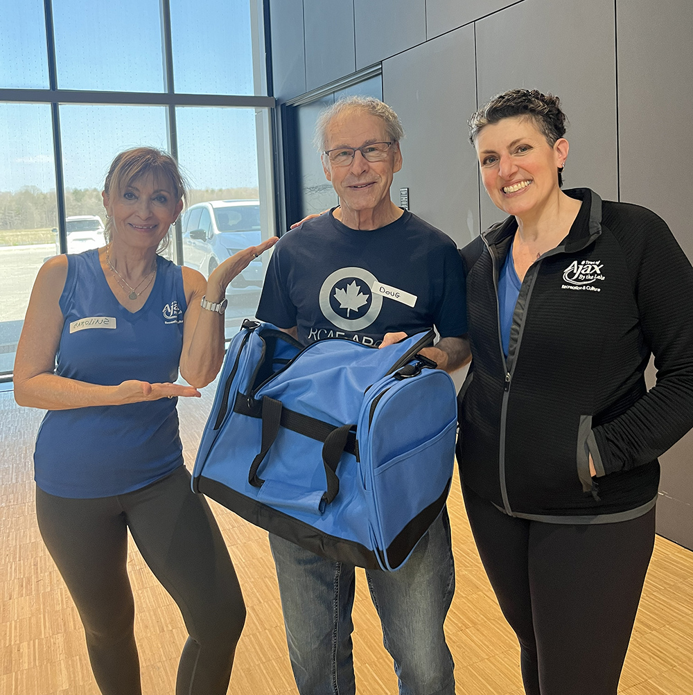 A Group Fitness member is presented with a prize by two Town of Ajax Fitness Instructors.