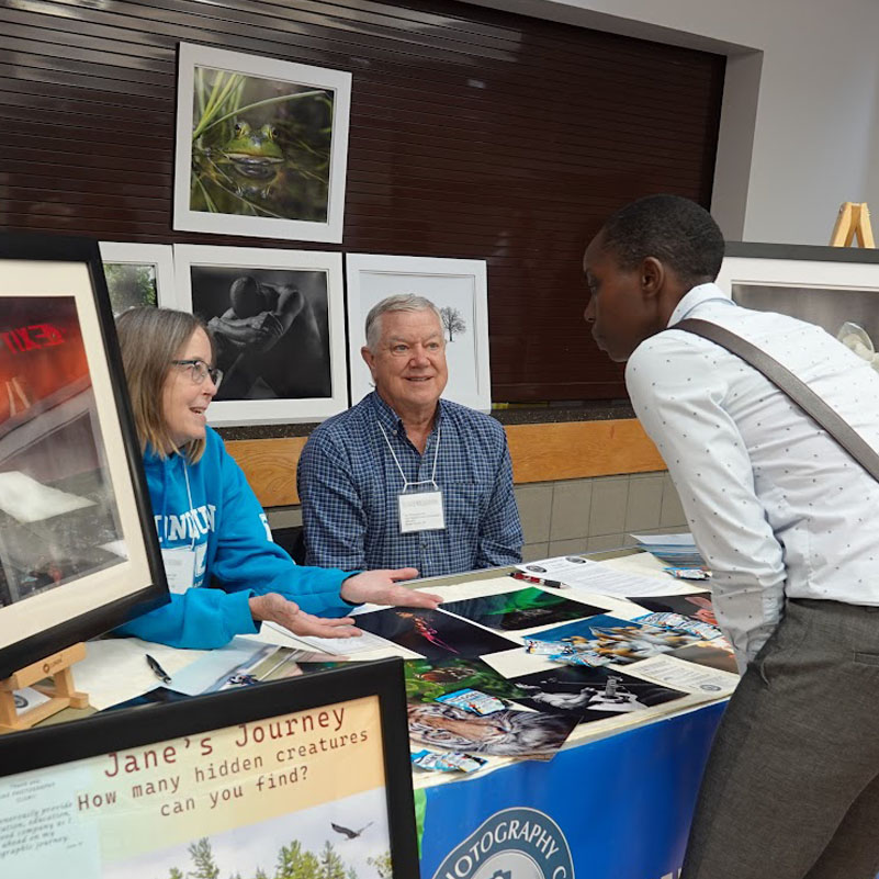 A woman visits a booth and speaks to two people at the 55+ Wellness and Information Fair.
