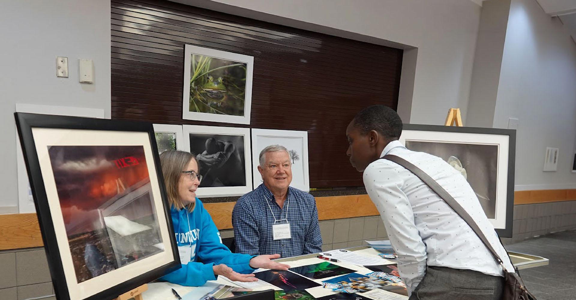 A woman visits a booth and speaks to two people at the 55+ Wellness and Information Fair.