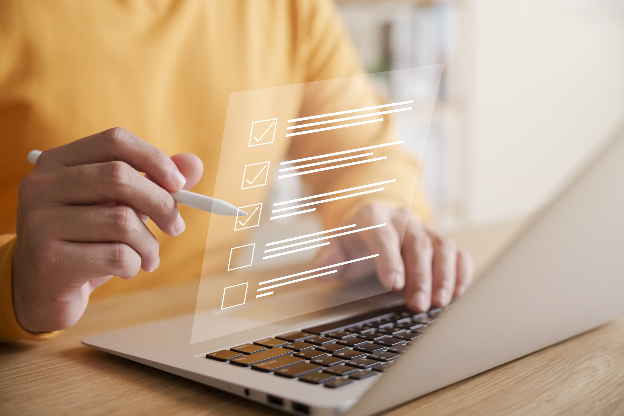 A person sits at their computer with a checklist.
