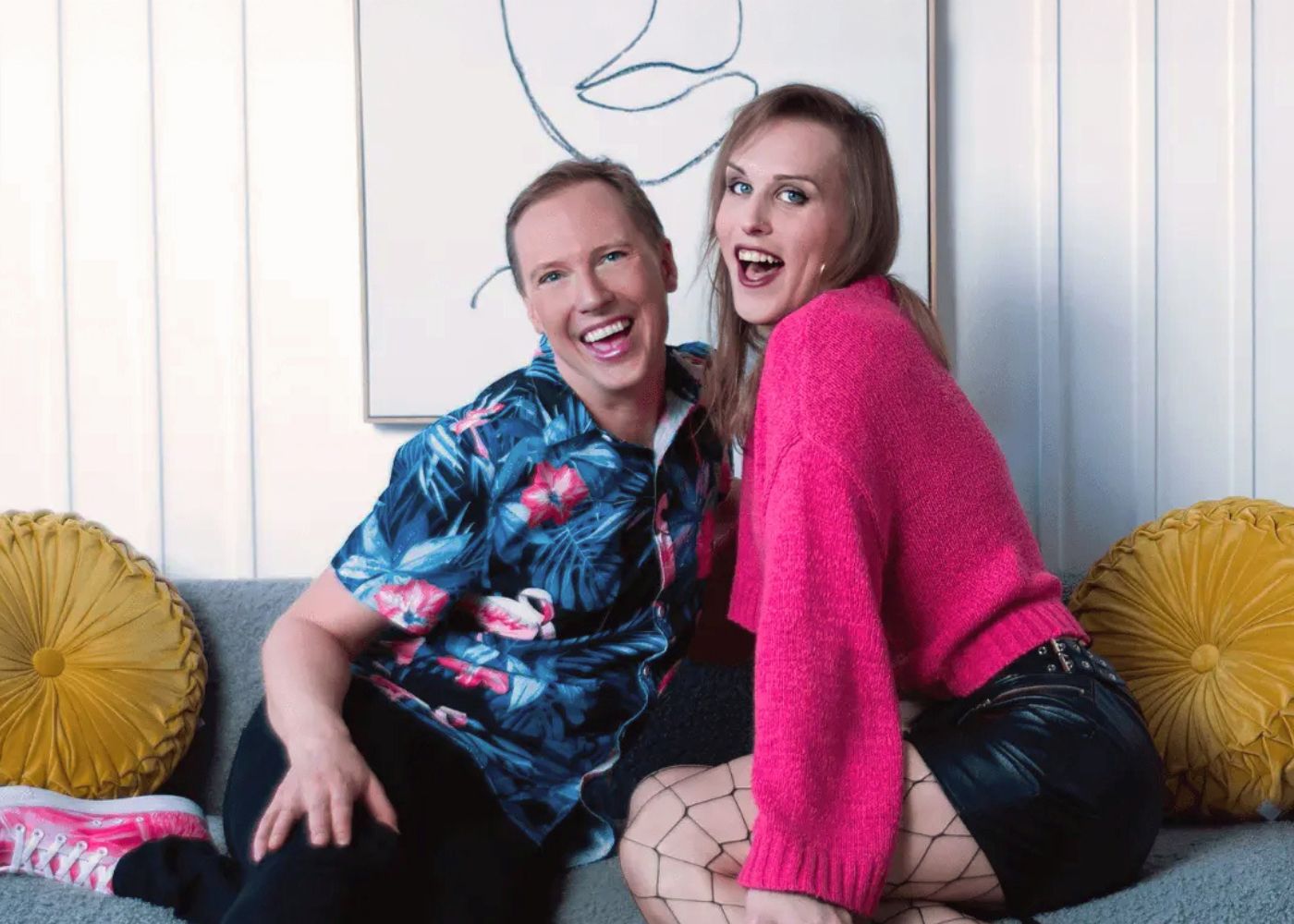 Two individuals sitting on a couch posing and smiling
