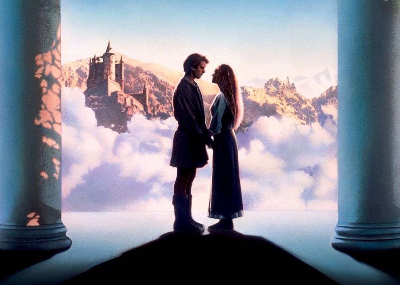 A man and women facing each other holding hands standing in a room the overlooks the clouds and a castle in the distance