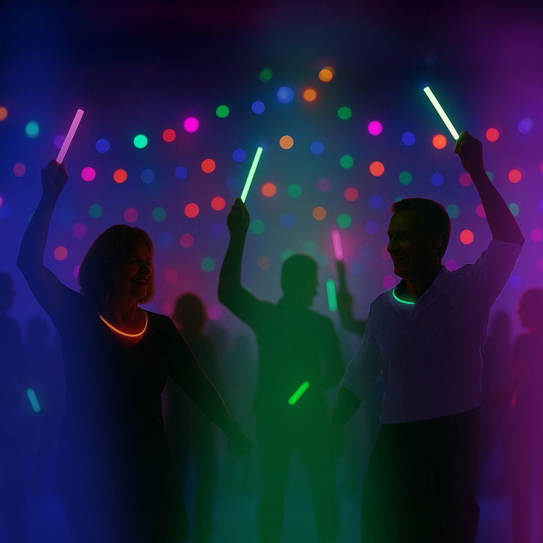 Silhouetted people dancing in a club-like setting, holding glowing light sticks, with colourful lights illuminating the background.