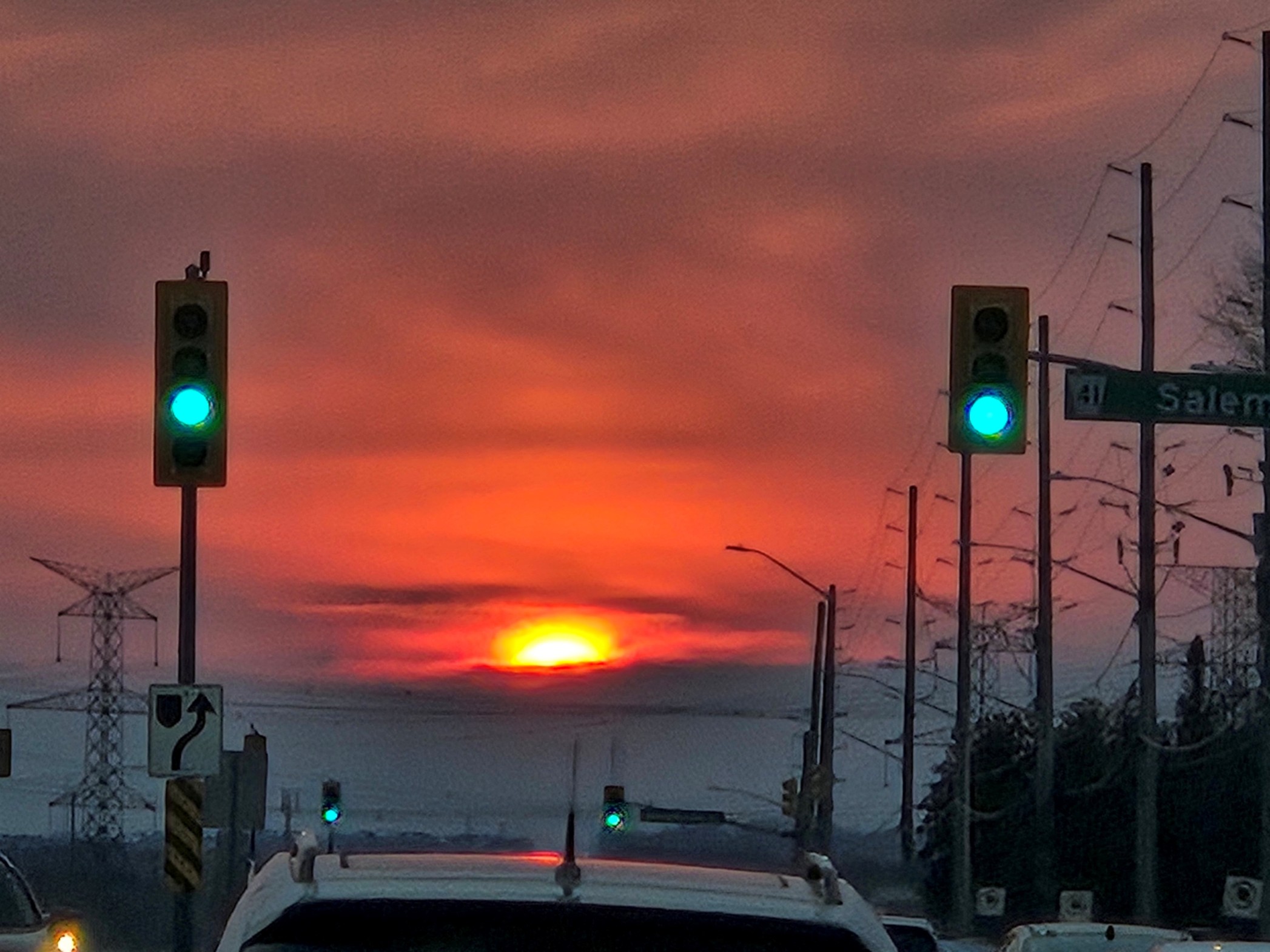Streetlights in the foreground are contrasted by a beautiful pink sunset in the background.